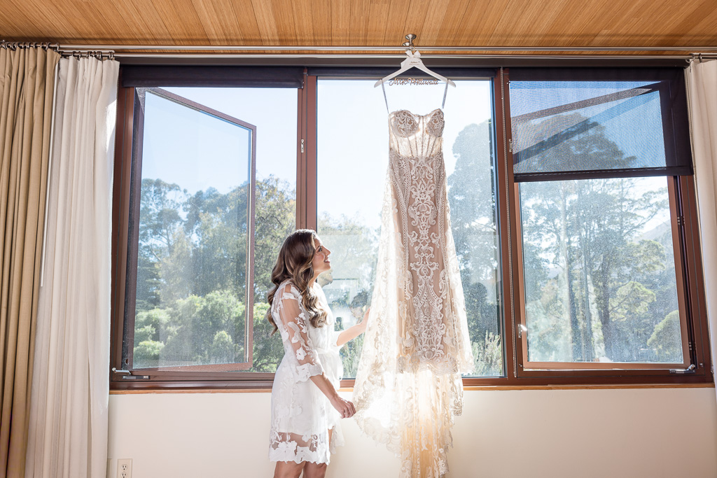 bride holding her dress while it hangs on a window