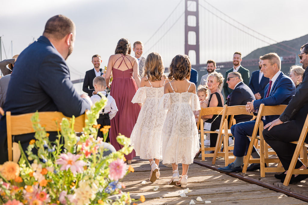 two flower girls walking up the aisle below the Golden Gate Bridge