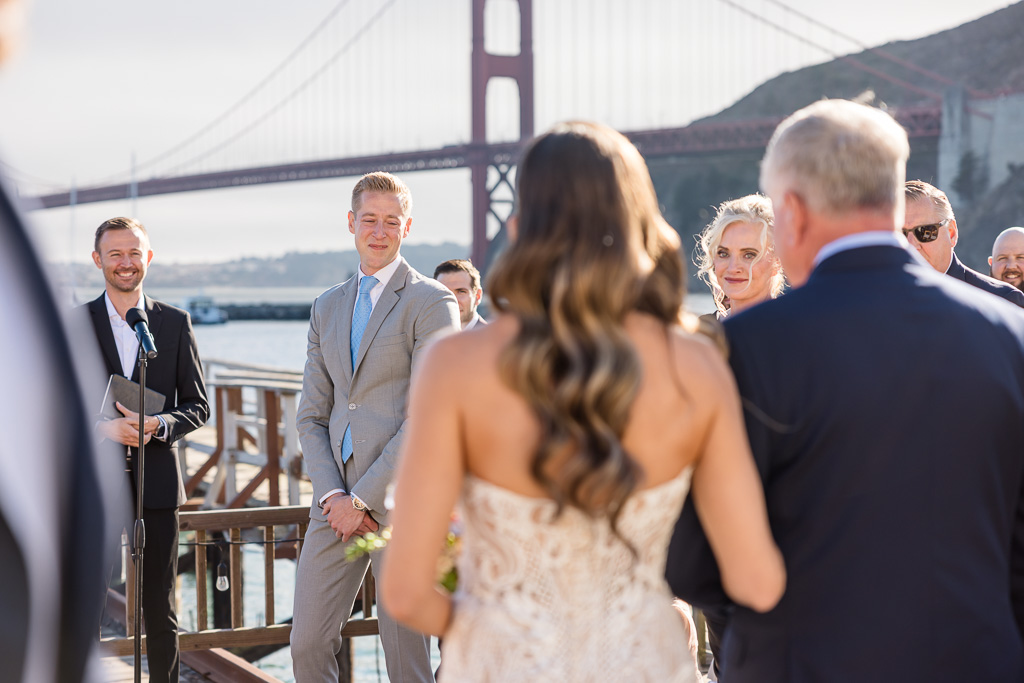 the moment right as the groom watches the bride and her dad walk down the aisle towards him