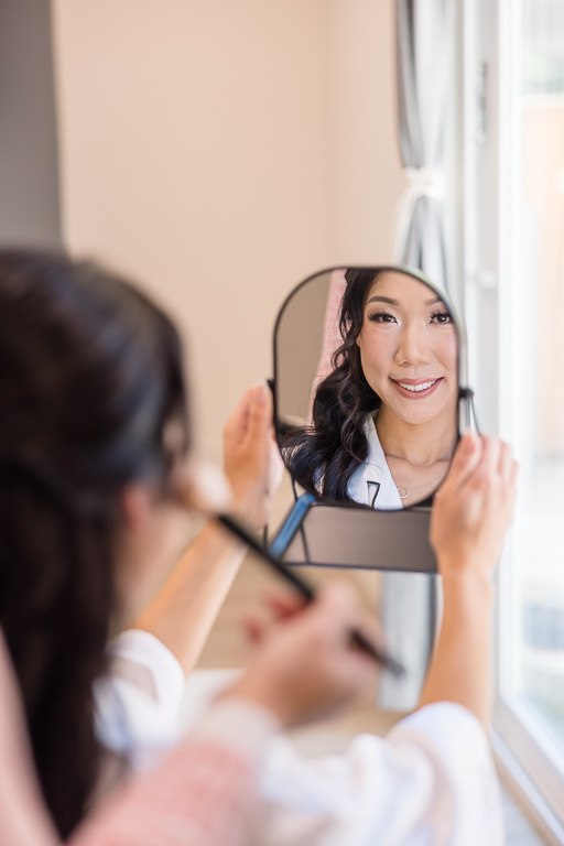 bride looking at her makeup in a handheld mirror