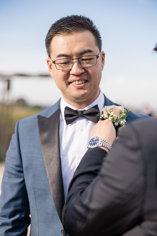 best man pinning boutonniere on groom