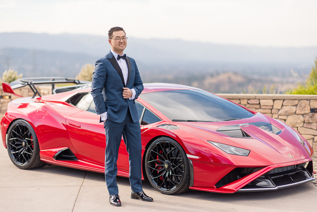 groom posing in front of a red Lamborghini Huracán STO