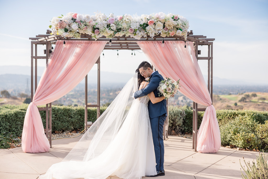 a hug between bride and groom in front of ceremony decor