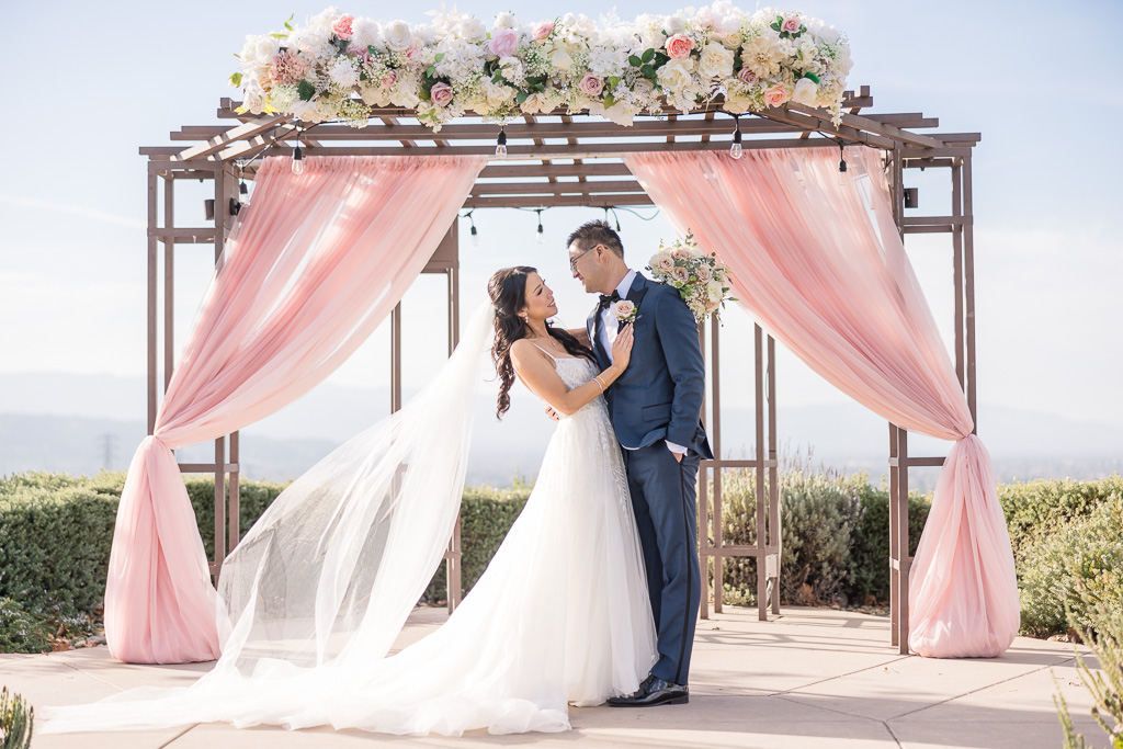 portrait of the bride and groom under wedding arch