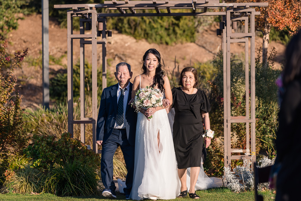 bride being walked up the aisle with her parents