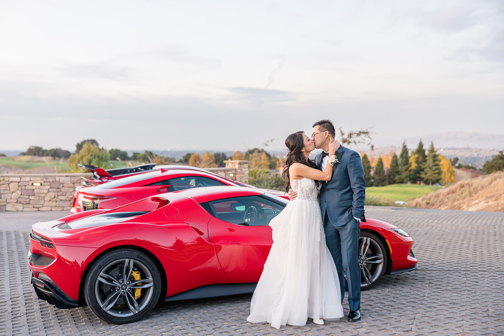 bride and groom kissing in front of a trio of red exotic supercars