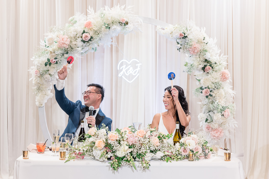 bride and groom holding up sticks with photos of them during reception game