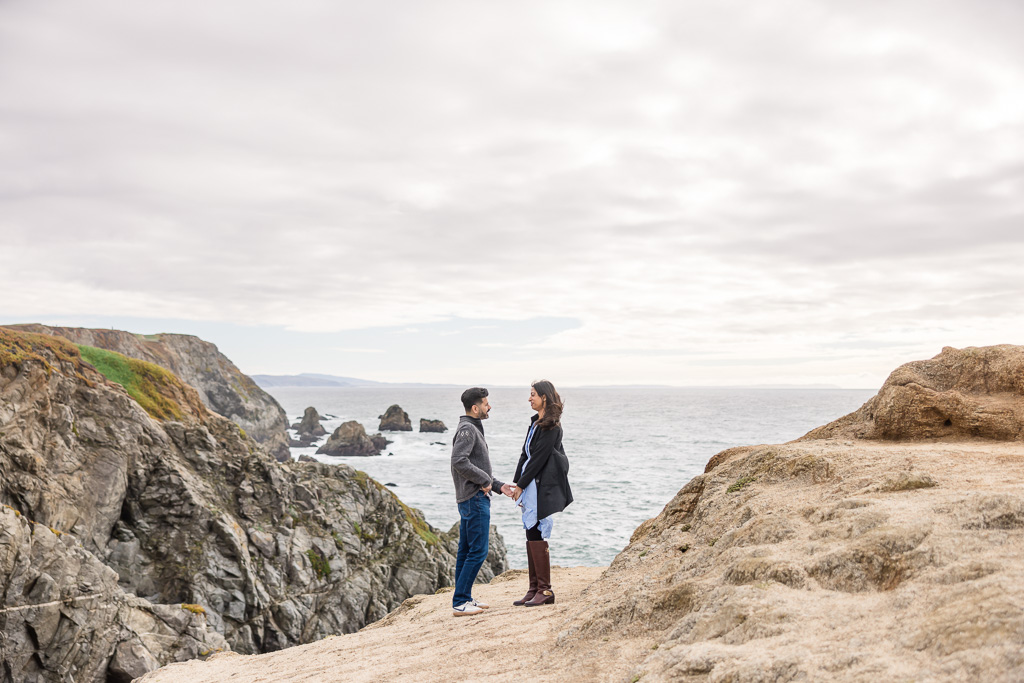 couple standing along the edge of the ocean cliffs