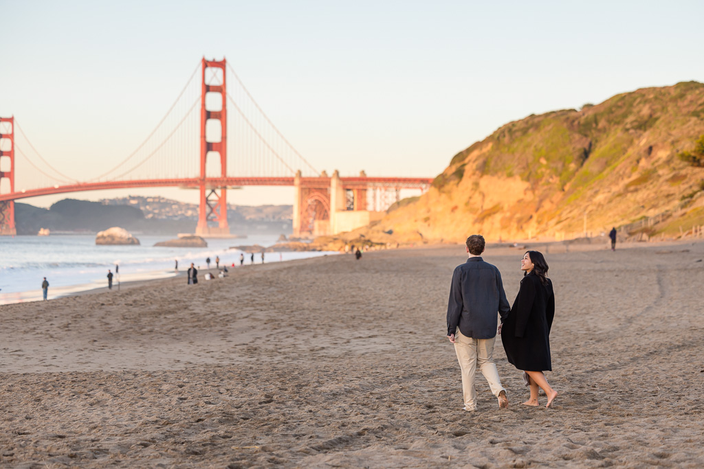 couple walking on the beach towards the Golden Gate Bridge