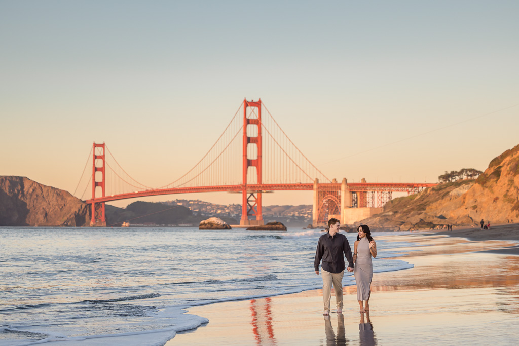 couple walking along colorful Baker Beach at sunset