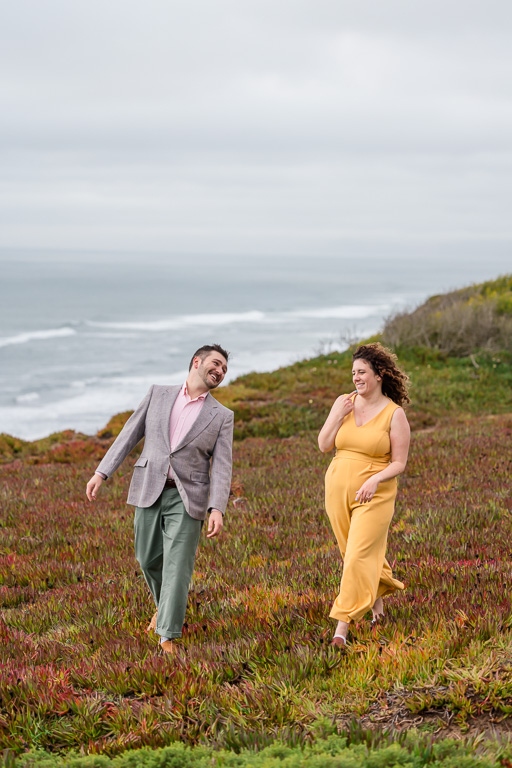 couple walking near the ocean signing to each other