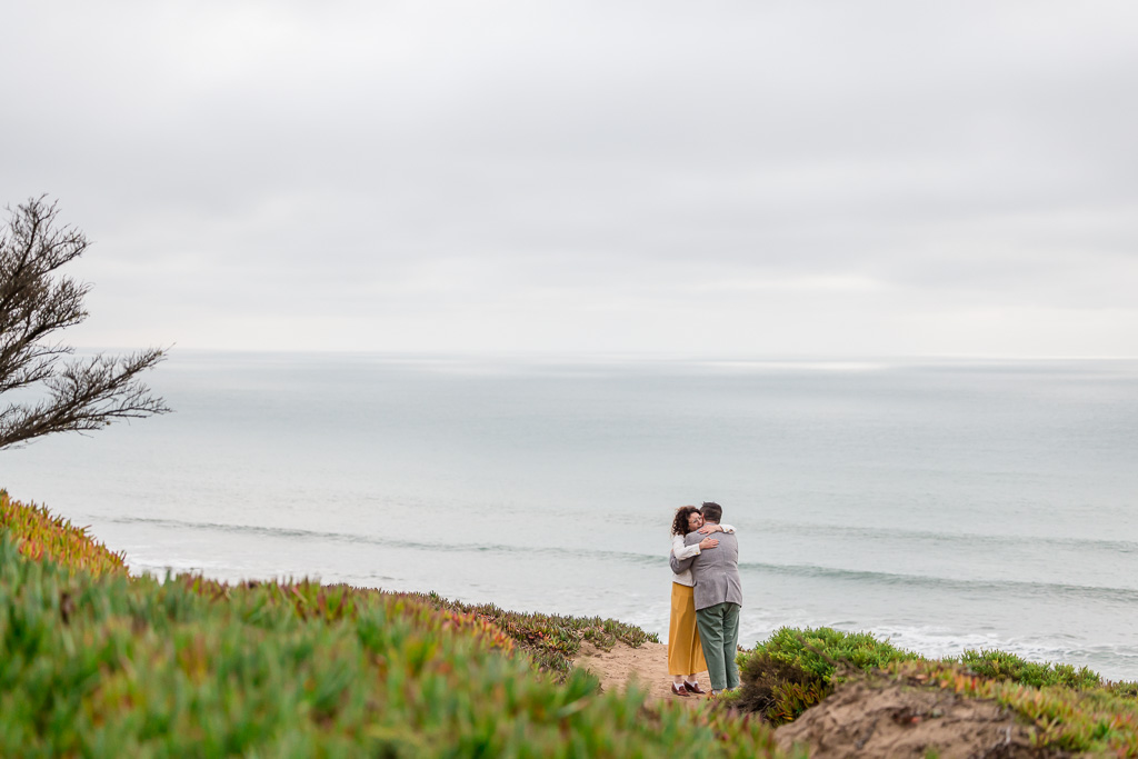 candid capture of couple hugging near the ocean