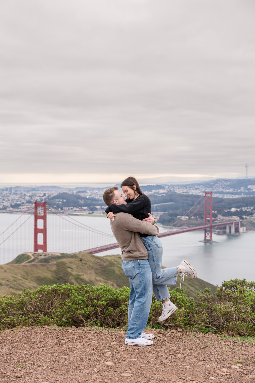 portrait of couple being lifted up near the Golden Gate Bridge