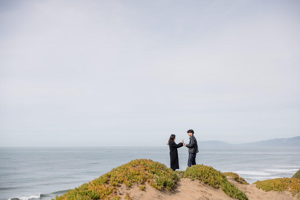 couple taking selfies on a cliff by the ocean