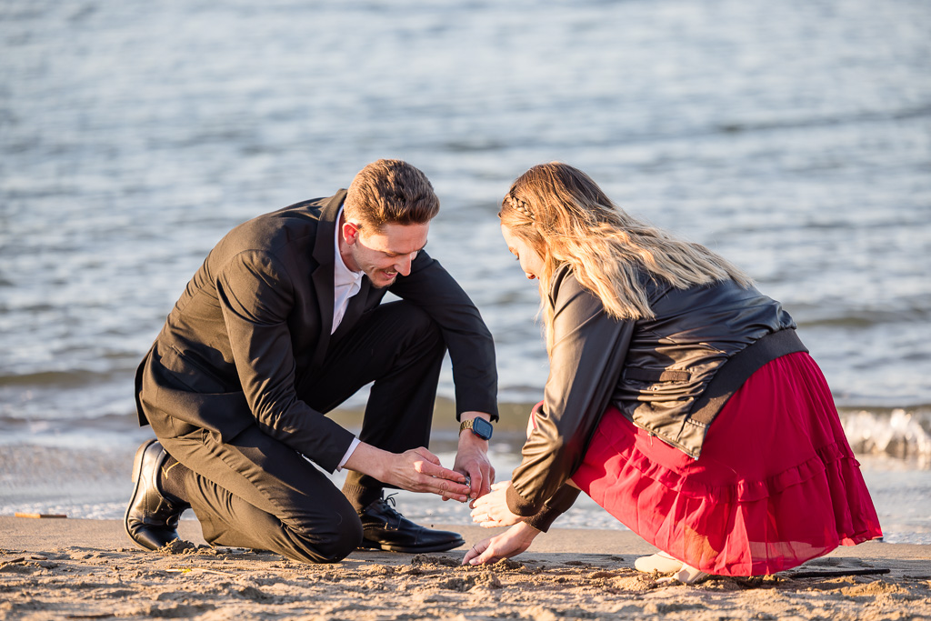 filling a small glass jar of sand from the spot where they got engaged