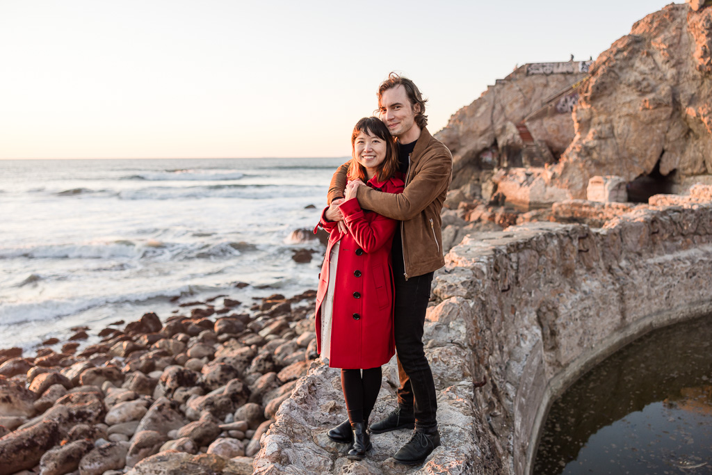 portrait of a young couple on the rocks by the ocean