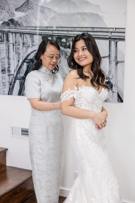 mom helping bride with the back of her dress