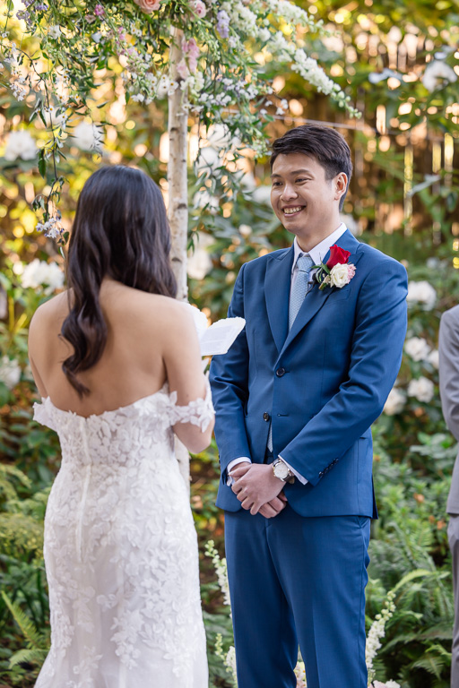 groom lovingly looking at bride as she reads her vows