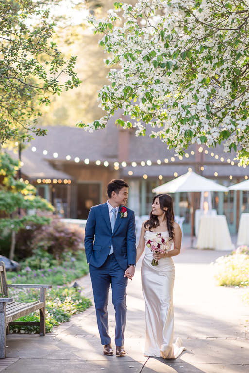 candid photo of bride and groom walking away from Outdoor Art Club in the background