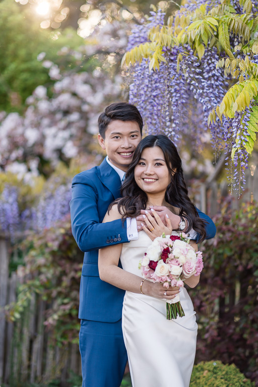 wedding portrait of bride and groom in front of wisteria blooms