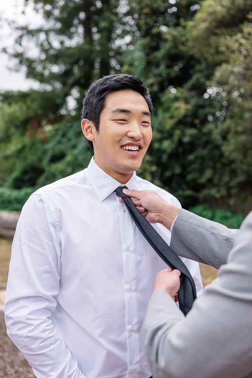 groom getting his tie adjusted by his friend
