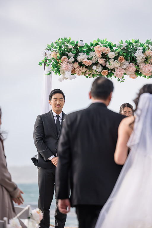 groom watching emotionally as bride and dad walk up the aisle towards him