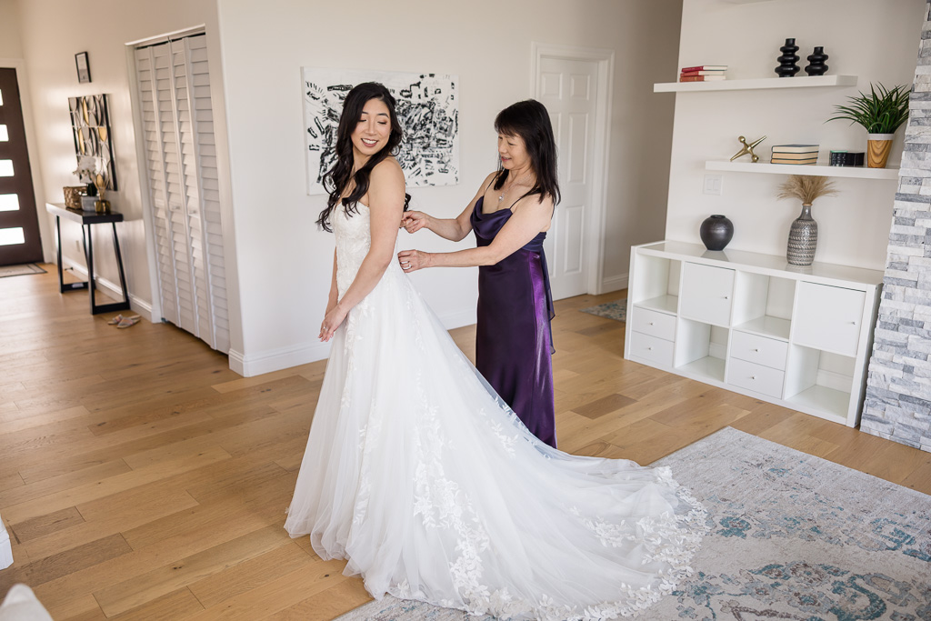 mom helping bride into her dress