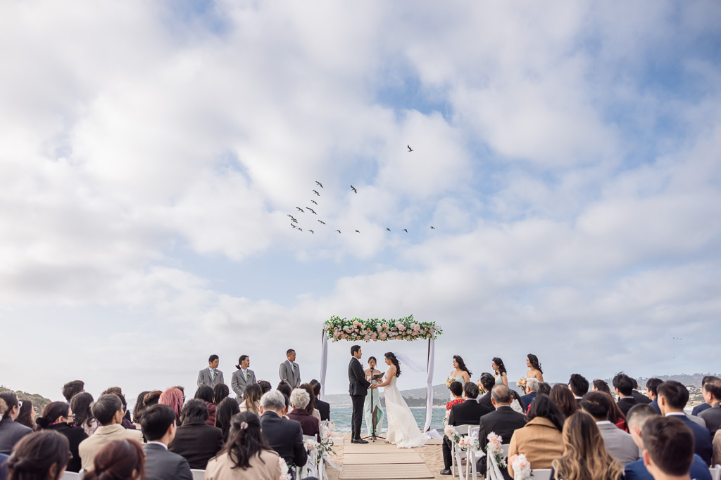 Monastery Beach wedding ceremony with blue sky and puffy white clouds