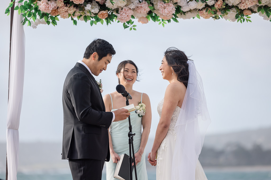 center angle up the aisle of groom reading written vows to bride