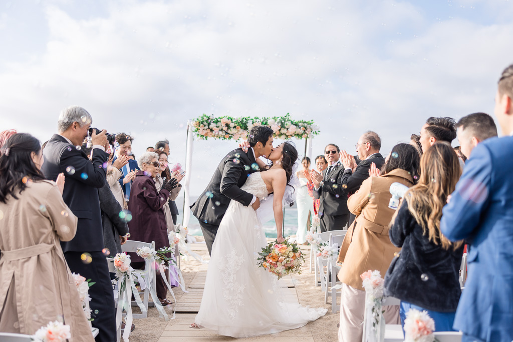 dip and kiss at the end of the aisle as guests blow bubbles