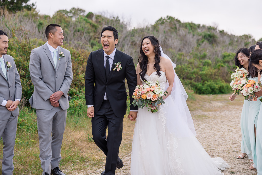groom laughing while holding hands with bride