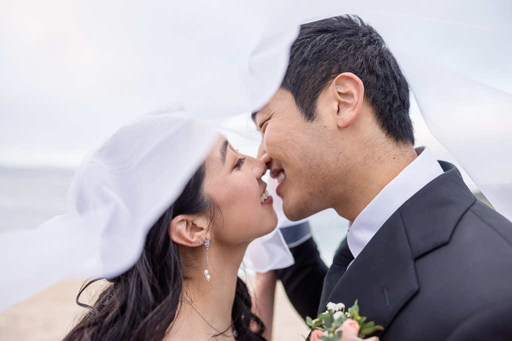 playful wedding photo kissing under veil