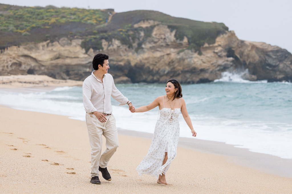 playfully running along the beach in matching white outfits