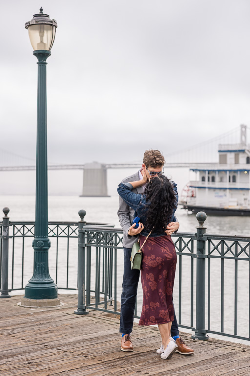 couple getting engaged near the Bay Bridge