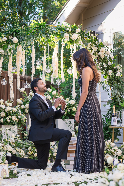 getting down on one knee in beautifully decorated backyard