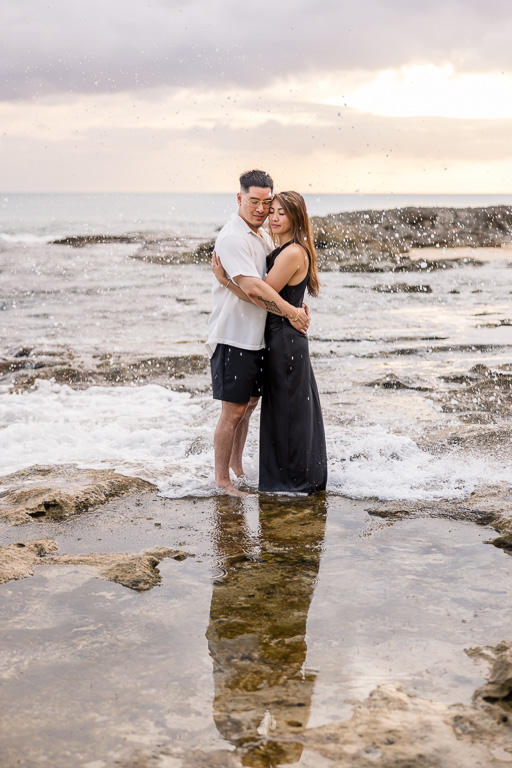 couple standing in front of a reflecting pool on the shores of Ko Olina at sunset