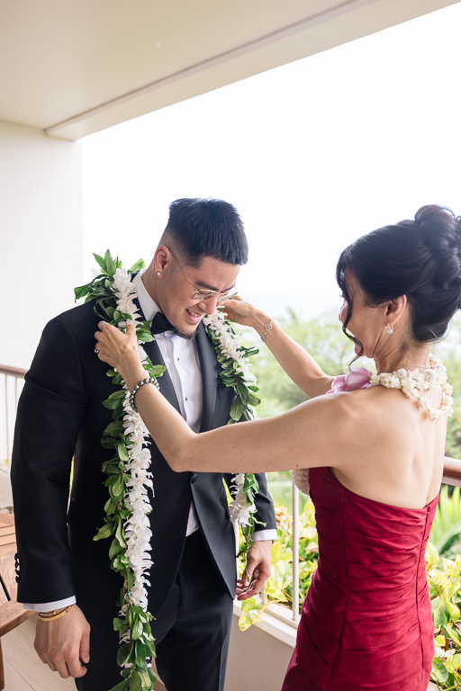 mom putting lei on the groom before wedding