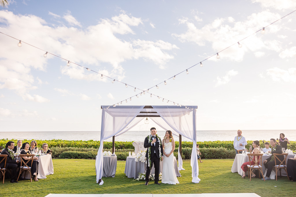 bride and groom giving a thank-you speech set against the blue skies of Oahu