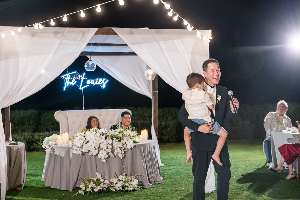 father of the groom giving a speech while holding a kid