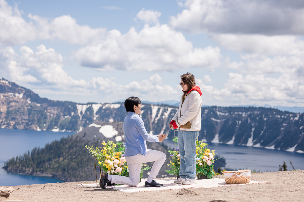 marriage proposal at Crater Lake with Wizard Island and Witches’ Cauldron and snow-lined mountains in the background