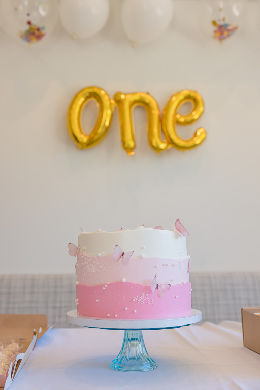 birthday cake with balloons spelling out the word one