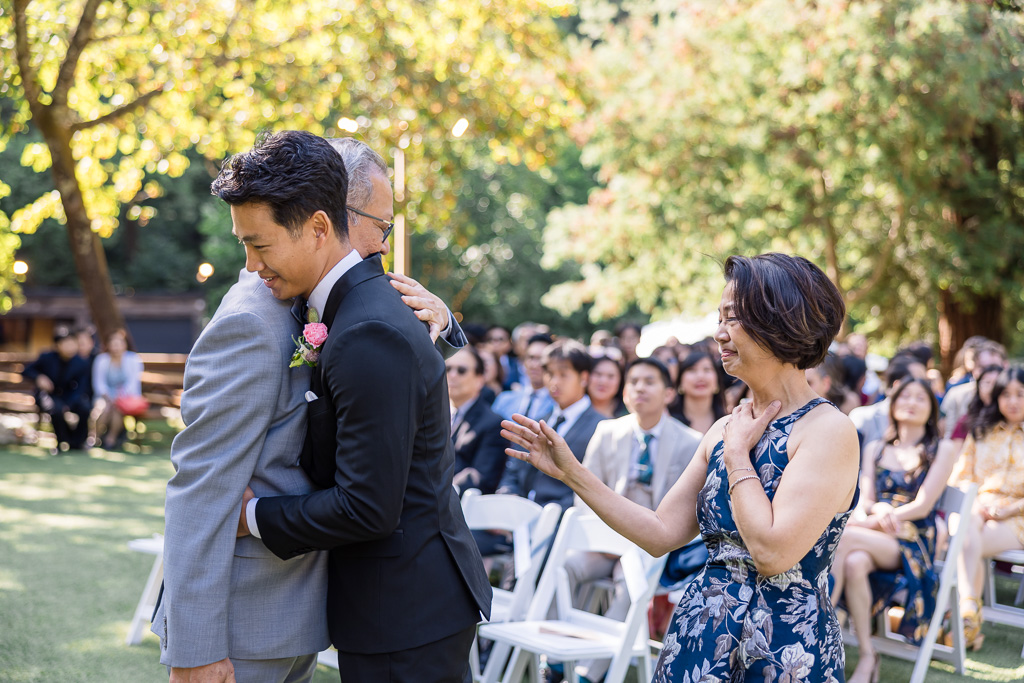 emotional moment with groom hugging his parents at the end of the aisle