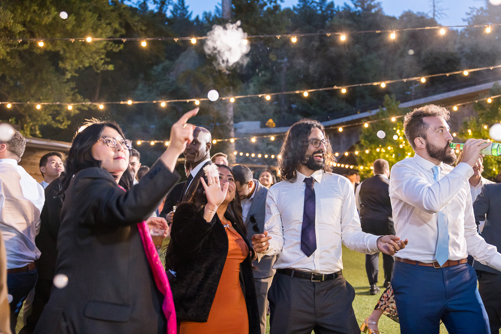 a wedding guest popping a fog bubble with her finger