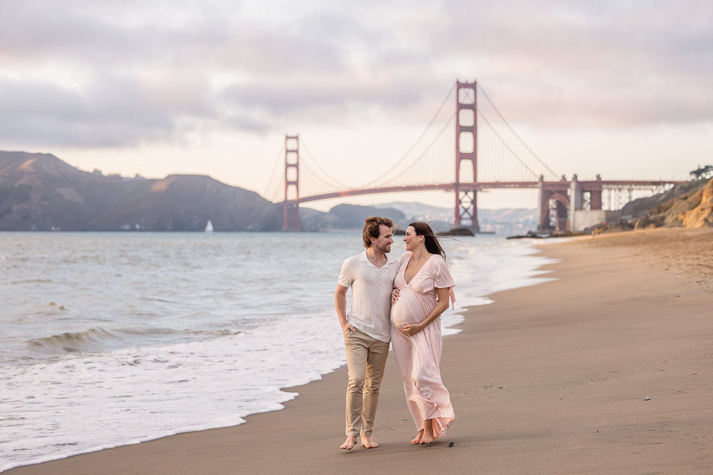 photo of future parents walking on a beach for maternity photos
