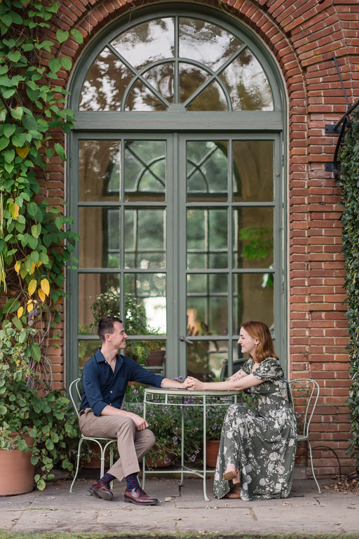 garden engagement photos sitting at cafe table outside