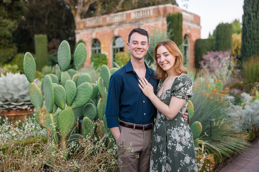 a couple posing in front of a large cactus plant