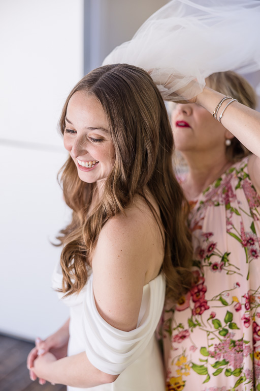 mom helping bride put on her veil