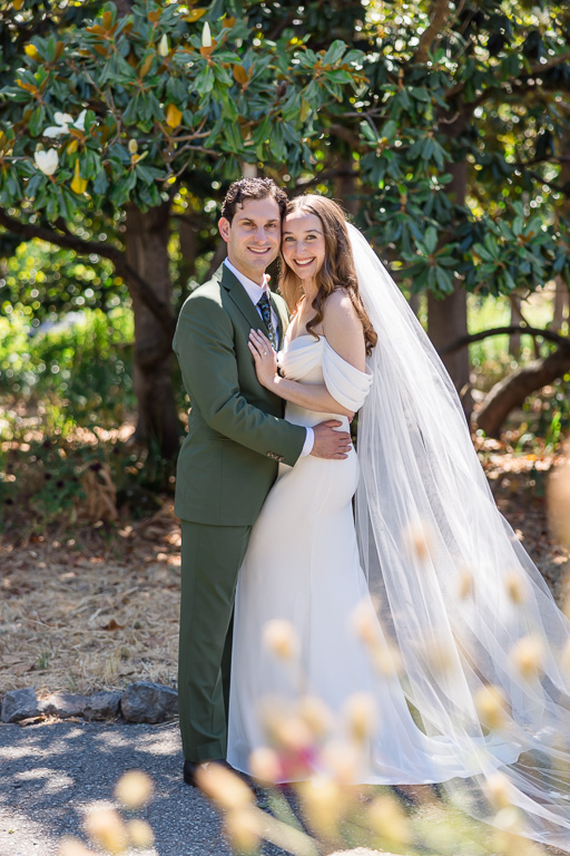 portrait of bride in white gown and groom in a sage green suit