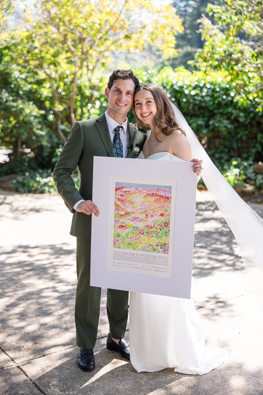 bride and groom holding up the finished floral-themed ketubah