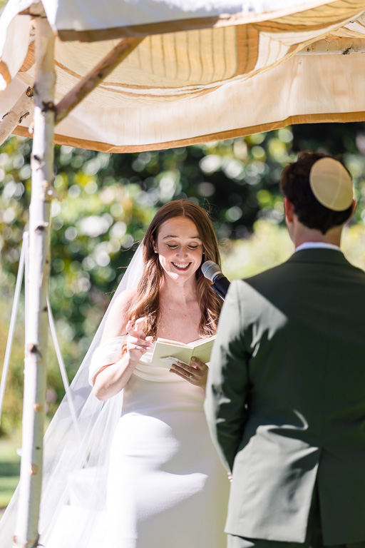 bride reading ceremony vows under chuppah